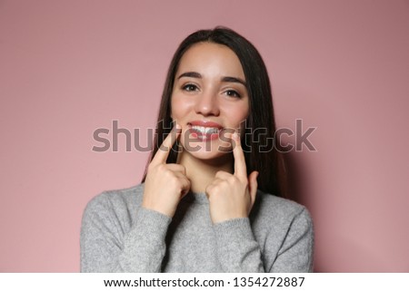 Woman showing LAUGH gesture in sign language on color background