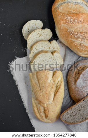 Bakery - gold rustic crusty loaves of bread on black chalkboard background. Flat lay, top view, copy space for your text