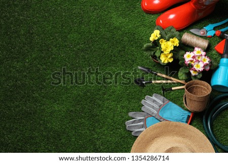 Flat lay composition with gardening equipment and space for text on green grass