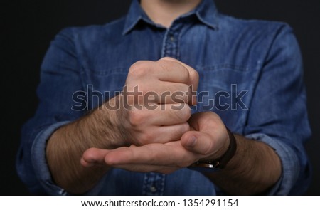 Man showing word CRUCIFY in sign language on black background, closeup