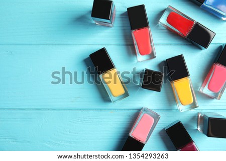 Bottles of nail polish on color background, top view with space for text