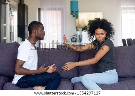 Black unhappy couple having quarrel at home arguing sitting on sofa in living room at home, husband makes excuses wife refuses listen dont believe him. Cheating, problems, fed up and break up concept Royalty-Free Stock Photo #1354297127