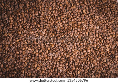 High resolution top view close up macro photo of look delicious dark roasted coffee beans, Flash light reflecting on the surface of the coffee beans make it look shinny beautiful and be nice for eat.