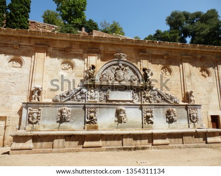 Baroque stone fountain decorated with sculptures, medallions, images of coats of arms and pilasters in the rays of the summer sun, Alhambra Palace, Granada, Andalusia, Spain. Scenic urban landscape.