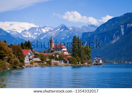 Panoramic view on the Brienz town on lake Brienz by Interlaken, Switzerland. Old fishing town with beautiful church and snow covered blue Alps mountains on background. Switzerland, Bohemia, Europe. Royalty-Free Stock Photo #1354332017