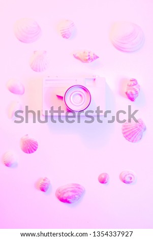 Summer background - The concept of leisure travel in the summer on a tropical beach seaside. retro camera with shell decoration. Flat lay minimal retrowave concept. glowing neon background