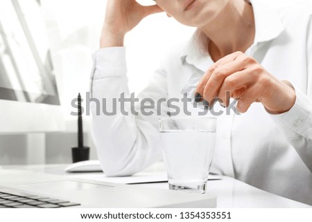 Painkiller tablet. A woman at work dissolves the effervescent painkiller tablet.