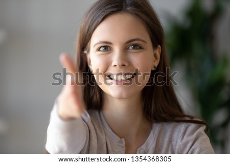 Smiling businesswoman holds out her hand to camera for handshake arm close up, focus on friendly face. Greeting gesture, negotiations, first impressions at acquaintance, hr and congratulations concept Royalty-Free Stock Photo #1354368305