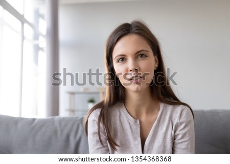 Head shot portrait young woman sitting on couch looking at camera having conversation using computer webcam modern tech talking with friend, girl recording vlog passing job interview distantly concept Royalty-Free Stock Photo #1354368368