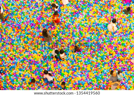 top aerial view of plastic balls pool with family childs and kids playing in the pool. Concept top view background colorful pixel.