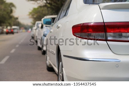 Closeup of rear, back side of white car parking in parking area beside the street with natural background in sunny day. The mean of transportation in modern world.
