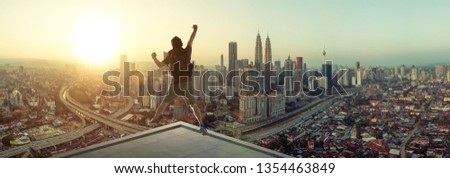 Young man jumping on rooftop with great cityscape sunrise view. Royalty-Free Stock Photo #1354463849