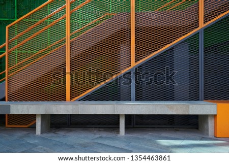 Grid steel wall and stone bench with cement ground background