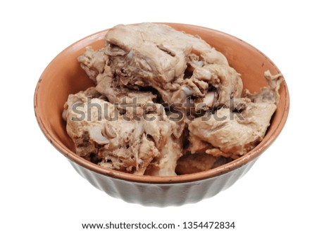 Chunks of boiled chicken bones with meat from a rustic soup in a clay bowl