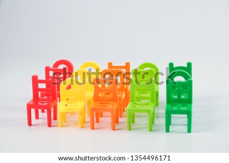 Colourful toy chairs arranged tidily & orderly isolated on white background