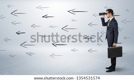 Young businessman standing and looking through binoculars with drawn arrows around