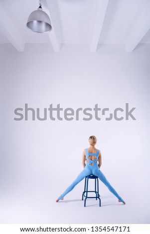 Skillful gymnast. Beautiful well built woman standing above the stool while practicing her movements