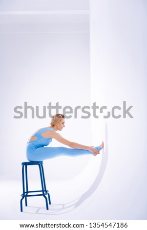 Beauty and grace. Positive fit woman touching her legs while sitting on the stool
