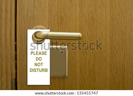Please do not disturb message, a common request for others not to disturb the motel or resort room occupants, on a paper cardboard tag hung on the door knob of a hotel