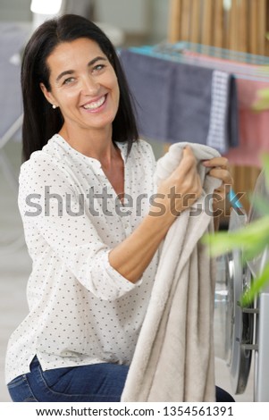 picture of woman putting towel in the washing machine