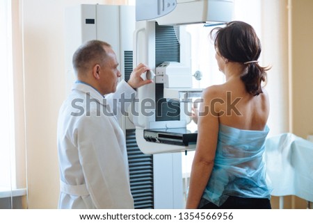 Male octor Standing Assisting Female Patient Undergoing Mammogram X-ray Tes Royalty-Free Stock Photo #1354566956