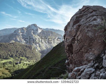 Mountain landscape,  a valley below the mountain slope behind a rock