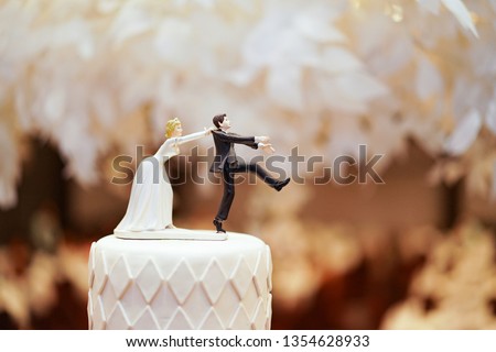 groom doll and statue is running away but bride can catch him finally. the funny wedding story doll on the top of cake. Royalty-Free Stock Photo #1354628933