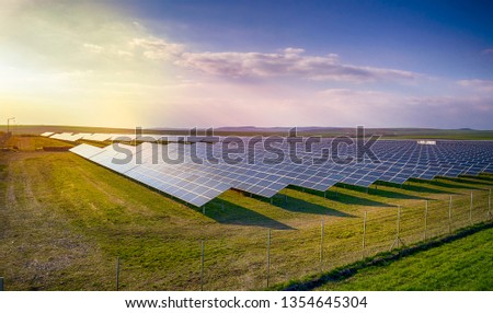 Solar panel produces green, environmentaly friendly energy from the setting sun. Aerial view from drone. Landscape picture of a solar plant that is located inside a valley
