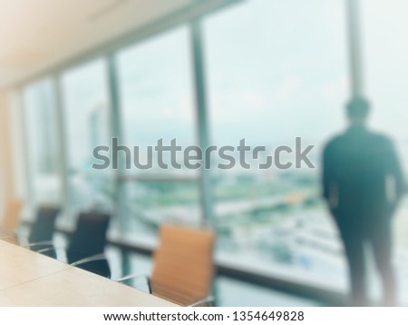 Conference table and blurred businessman looking at the large glass window with city view Royalty-Free Stock Photo #1354649828