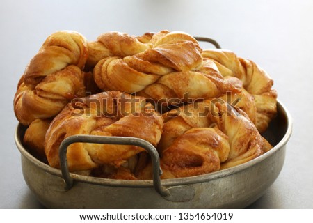 Freshly baked cinnamon buns. Cinnamon roll pastries in a pile in an antique metal tray close up stock photo