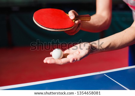 A young man is playing ping pong. He holds a ball and a racket in his hands Royalty-Free Stock Photo #1354658081