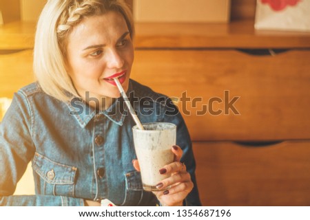 Beautiful girl in a cafe enjoying a cold cocktail. Hipster girl holding summer cocktail. Refreshment drink in sunny day
