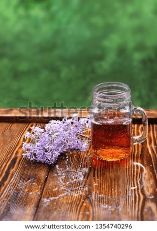 Cup of tea with lilac flowers in garden. Rainy day, spring season. copy space