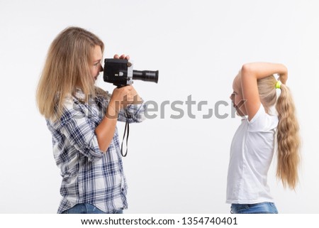 People, photography and hobby concept - woman using an old fashioned camera and photographing a little girl on white background