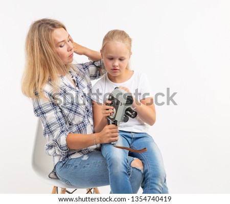 Photo, photographer and retro camera concept - young woman and her teen daughter using vintage camera on white background