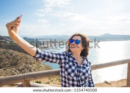 Travel, vacation and holiday concept - Happy young woman taking selfie over beautiful landscape