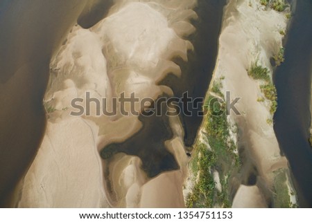 Top view of a sandy beach with a beautiful pattern of dunes, grass and shrubs formed from the water, of autumn. Photography with drone in the form of texture and background