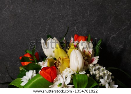 Beautiful large bouquet of red and white tulips, white chrysanthemums, yellow orchids, variegated irises with a copy space on a gray stone background