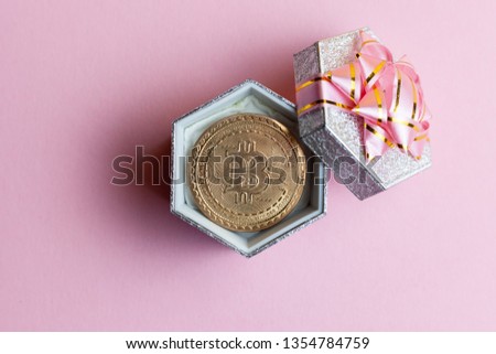 bitcoin lies in small gift box at pink background.