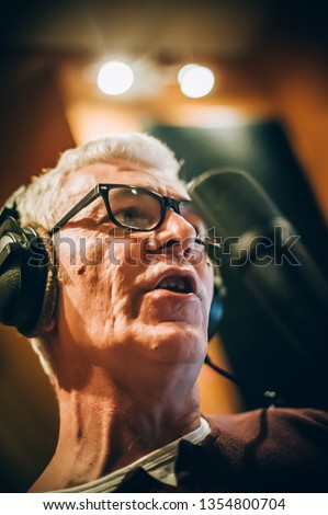 Behind the scene. Famous alternative male singer practice singing on the microphone in the messy recording music studio. Musician live singing