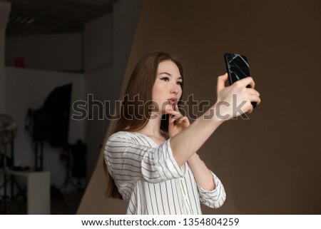 young asian woman taking selfie in photo studio on smartphone