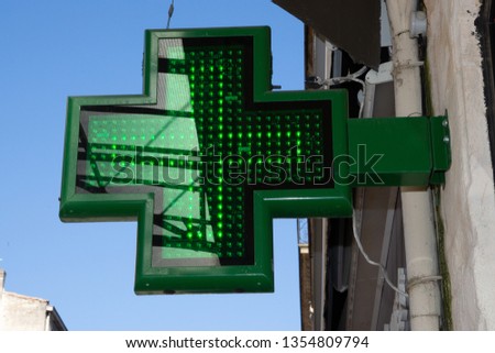 green pharmacy sign outside a pharmacy store in street