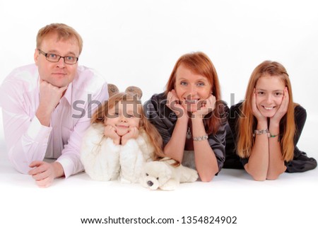 Smiling happy family of four lying on the floor in studio on white background