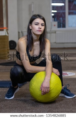 The girl is engaged with a  ball in the gym