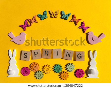 Spring, word in wooden alphabet letters with rabbits, flowers, butterflies and birds as a frame