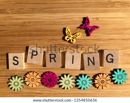 The word Spring in wooden 3d alphabet letters with flower s and butterflies on a bamboo board with copy space