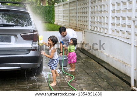 Picture of two little children looks happy while helping their father to washing a car at home