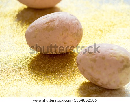 three pink eggs on golden dust background with copy space. happy easter composition