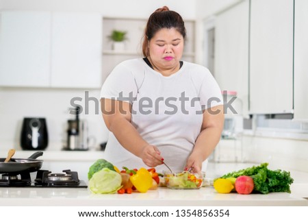 Picture of fat Asian woman preparing fruits and vegetable salad in the kitchen