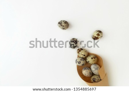 Quail eggs in brown craft wrapping paper on a white background. Creative easter concept. Top view, flat lay. Minimalistic composition, copy space for text. 